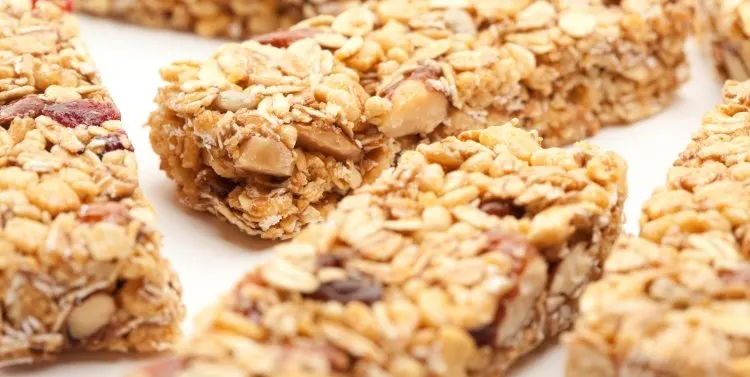 Barritas de granola con avena, almendras y trozos de fruta seca sobre fondo blanco