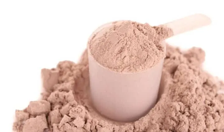Cucharón medidor lleno de proteína en polvo sabor chocolate sobre un montón del mismo polvo