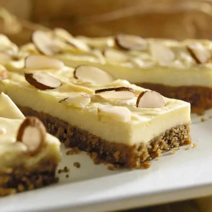 Barras con base de galleta compactada y cobertura clara con almendras laminadas, cortadas en porciones